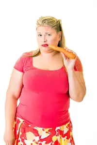 mujer-rubia-gorda-infeliz-con-la-zanahoria-cruda-82488061.webp