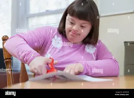 nina-con-sindrome-de-down-cortando-un-papel-con-tijeras-2a93h38.webp